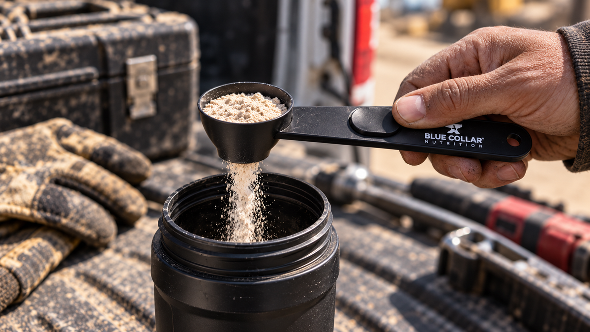 BCN Sliding Powder Scoop dispensing protein powder into a shaker bottle on a rugged jobsite workbench.