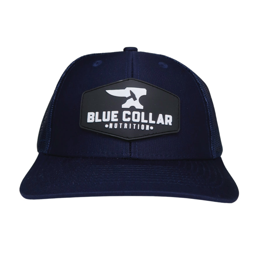 BCN Classic Trucker Curved Hat in navy blue with hexagonal 3D PVC patch — raised white logo, front view of pvc patch trucker hat